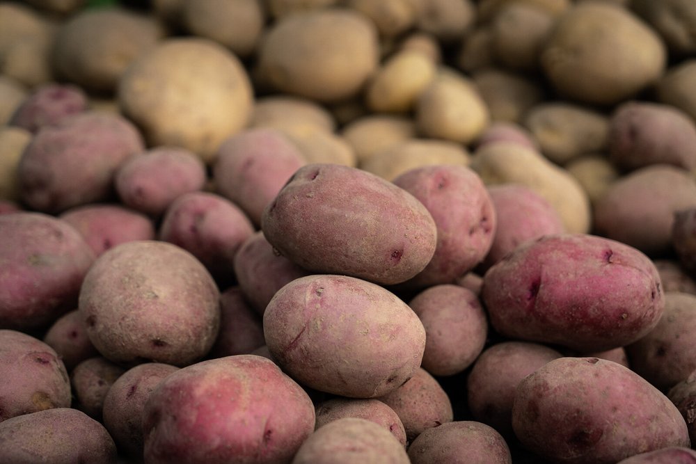 A close-up view of a pile of fresh, unwashed red and yellow potatoes, showcasing their earthy textures and natural colors, ideal for culinary use and healthy eating.